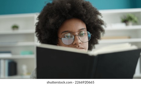 African american woman student reading book at library university - Powered by Shutterstock