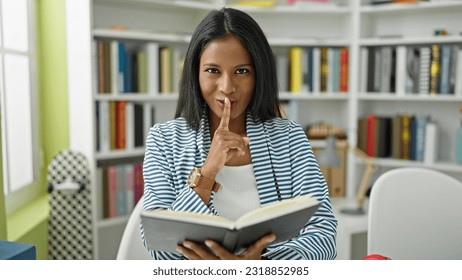 African american woman student reading book doing silence gesture at library university - Shutterstock ID 2318852985