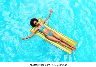 African American Woman In Swimsuit Floating In Inflatable Matress At Swimming Pool, Overhead View