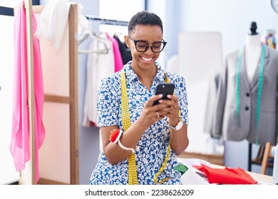 African american woman tailor smiling confident using smartphone at tailor shop - Powered by Shutterstock