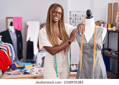 African american woman tailor smiling confident leaning on manikin at tailor shop - Powered by Shutterstock