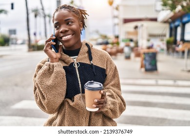 African american woman talking on the smartphone drinking coffee at street