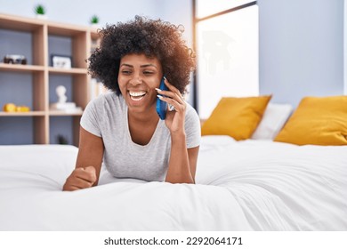 African american woman talking on smartphone lying on bed at bedroom - Powered by Shutterstock