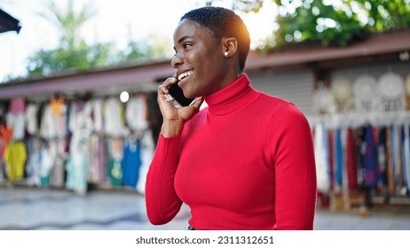 African american woman talking on smartphone smiling at street market - Shutterstock ID 2311312651