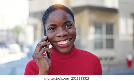 African american woman talking on smartphone smiling at street - Shutterstock ID 2311313329