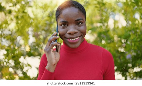 African american woman talking on smartphone smiling at park - Shutterstock ID 2311313341