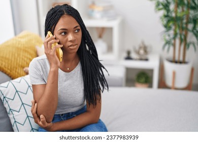 African american woman talking on smartphone with serious expression at home - Powered by Shutterstock