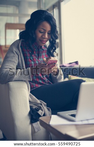 African American woman typing messages on phone in office. 