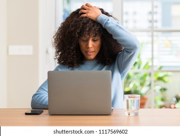 African American Woman Using Laptop Computer At Home Stressed With Hand On Head, Shocked With Shame And Surprise Face, Angry And Frustrated. Fear And Upset For Mistake.