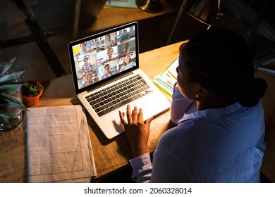 African american woman using laptop for video call, with diverse elementary school pupils on screen. communication technology and online education, digital composite image.