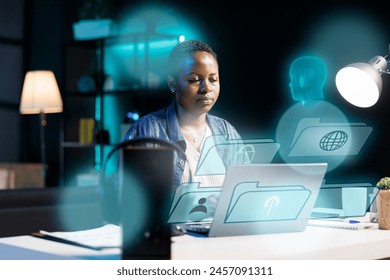 African american woman using laptop, interacting with artificial intelligence assistant using AR tech. BIPOC person working with AR technology, giving commands to virtual AI companion - Powered by Shutterstock