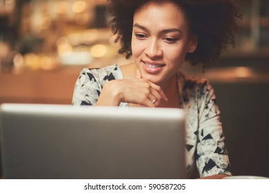 African American Woman Using Laptop In Cafe While Sitting