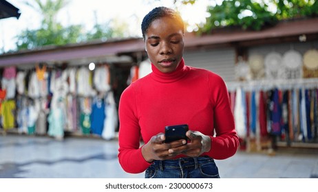 African american woman using smartphone with serious expression at street market - Shutterstock ID 2300000673