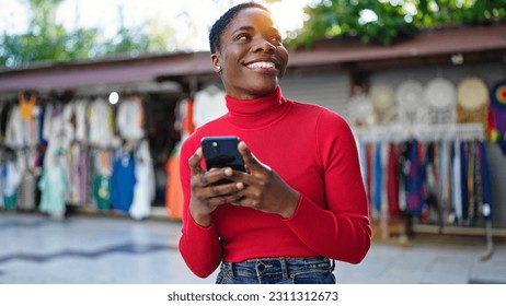 African american woman using smartphone smiling at street market - Shutterstock ID 2311312673
