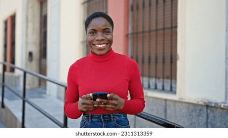 African american woman using smartphone smiling at street - Shutterstock ID 2311313359