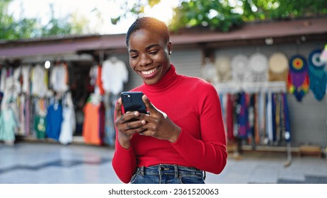 African american woman using smartphone smiling at street market - Shutterstock ID 2361520063