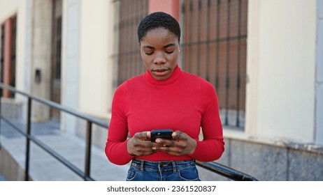 African american woman using smartphone with serious expression at street - Shutterstock ID 2361520837