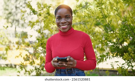 African american woman using smartphone smiling at park - Shutterstock ID 2361520881
