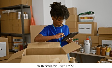 African american woman volunteer using touchpad checking products on package at charity center - Powered by Shutterstock