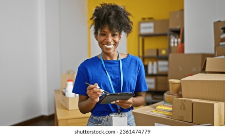 African american woman volunteer writing on touchpad smiling at charity center - Powered by Shutterstock