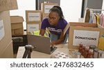 African american woman volunteers at donation center using laptop indoors