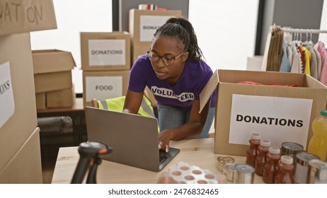 African american woman volunteers at donation center using laptop indoors - Powered by Shutterstock