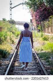 African American Woman Walking Along The Train Tracks In A Rural Location.