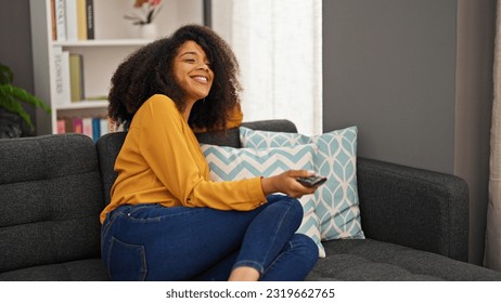 African american woman watching tv sitting on sofa at home - Powered by Shutterstock