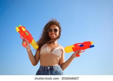 African American Woman With Water Guns Against Blue Sky, Low Angle View