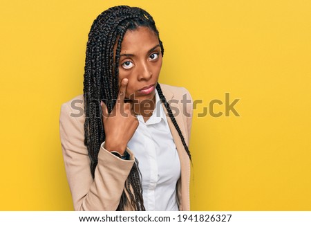 African american woman wearing business jacket pointing to the eye watching you gesture, suspicious expression 