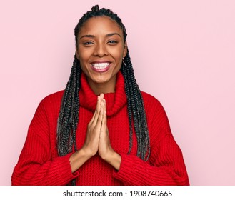 African American Woman Wearing Casual Winter Sweater Praying With Hands Together Asking For Forgiveness Smiling Confident. 