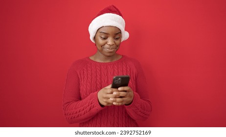 African american woman wearing christmas hat using smartphone over isolated red background - Powered by Shutterstock