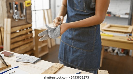 African american woman wearing safety gloves in a woodworking studio - Powered by Shutterstock