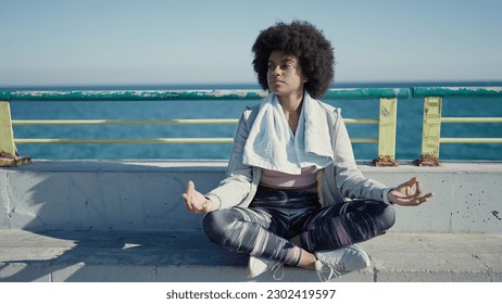 African american woman the from yoga on promenade by Pikwizard sea doing sportswear in