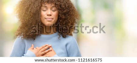 African american woman wearing a sweater smiling with hands on chest with closed eyes and grateful gesture on face. Health concept. Stockfoto © 