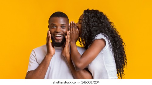 African American Woman Whispering Gossips Into Her Man Ear, yellow studio background, panorama