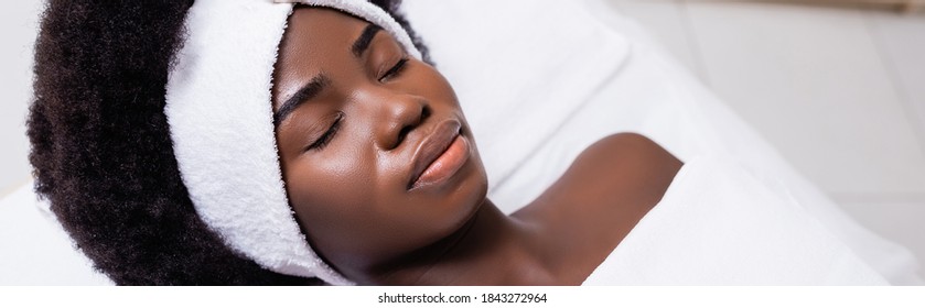 African American Woman In White Headband Lying On Massage Table In Spa Salon, Banner