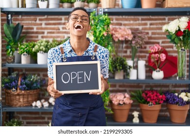 African american woman working at florist holding open sign smiling and laughing hard out loud because funny crazy joke. 