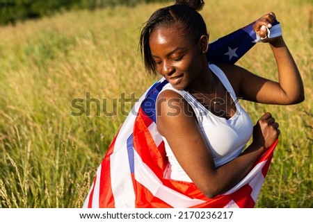 African american woman wrapped in american flag flutters waving in the wind. Happy 4th of July! Independence Day celebrating. Stars and stripes. Freedom concept.