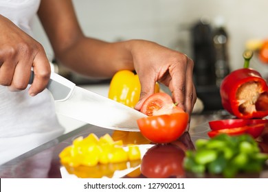 African  American womans hand slicing a tomatoe