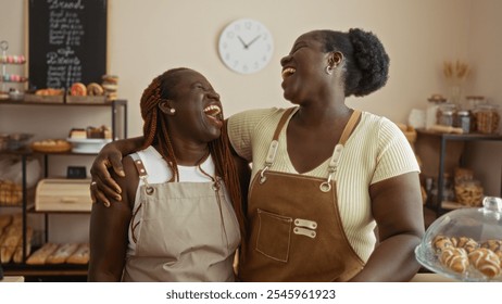 African american women bakers laughing and sharing a moment in a cozy bakery shop, surrounded by delicious pastries, bread, and a welcoming interior. - Powered by Shutterstock