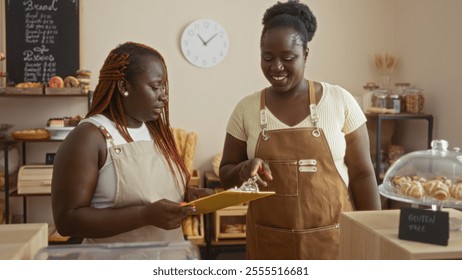 African american women bakery workers discussing orders in a cozy bakery interior with pastries and bread displayed. - Powered by Shutterstock