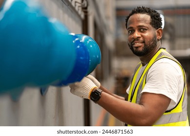 African American worker is hanging his safety helmet on the rack inside the heavy industrial factory for protection and accident prevention concept - Powered by Shutterstock