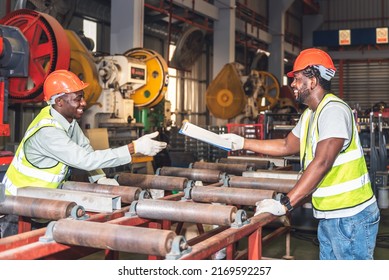 African American Worker Man Are Handing Industrial Machinery Maintenance Report To His Colleague, At Workplace Is Metal Sheet Factory, To Worker And Industry Concept.