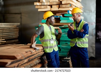 African American worker talking to his foreman while working at timber warehouse. - Powered by Shutterstock