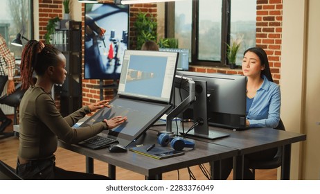 African american worker using game developing software on computer and touchscreen, working with graphics and professional interface. Digital artist designing CGI and virtual artistic content. - Shutterstock ID 2283376049