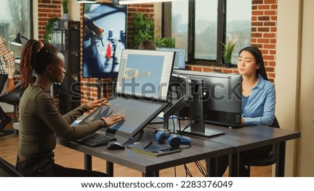 African american worker using game developing software on computer and touchscreen, working with graphics and professional interface. Digital artist designing CGI and virtual artistic content.