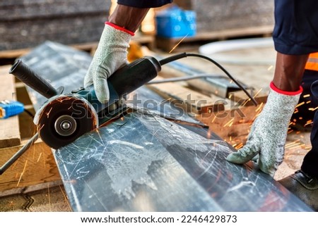 African American worker using power tools, angle grinder cutting sheet of metal
