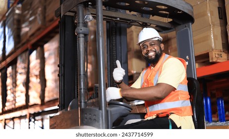 African American worker in warehouse, International export business concept. Industrial driver working at factory warehouse. Factory worker male showing thumb up on forklift. Paper factory. - Powered by Shutterstock