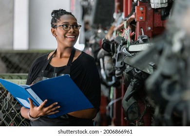 African American Worker Women Wear Spectacles Make A Note Of The Product List On Clipboard In Factory Auto Parts. Female Employee Business Warehouse Motor Vehicle.